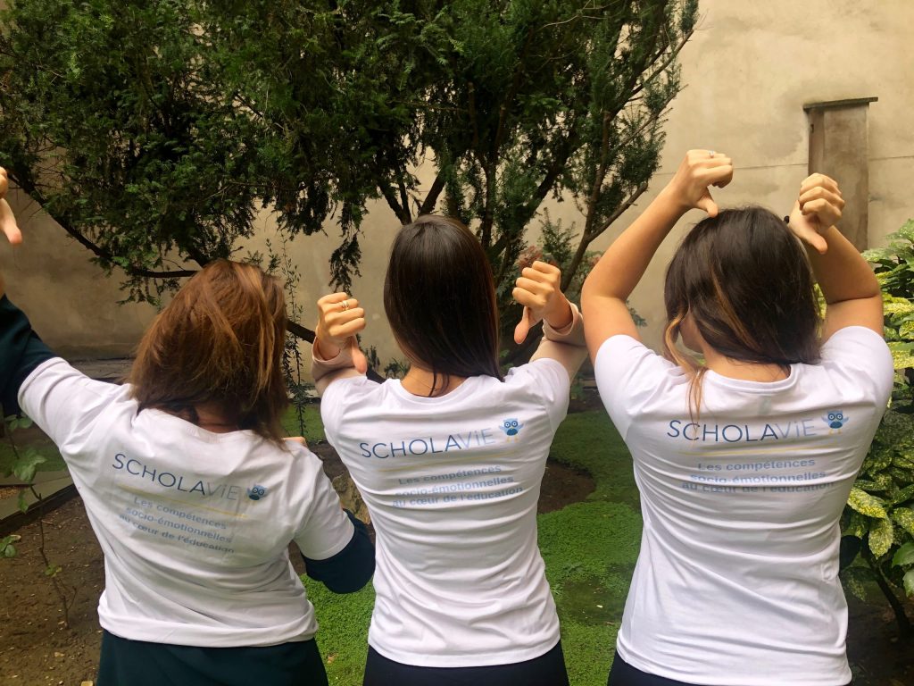 3 femmes de l'équipe ScholaVie de dos avec un tshirt où est affiché le logo ScholaVie